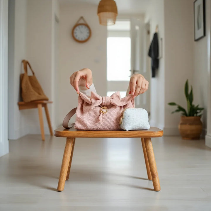 Händer som ordnar barnaccessoarer på bänk i ljust hem med neutrala toner