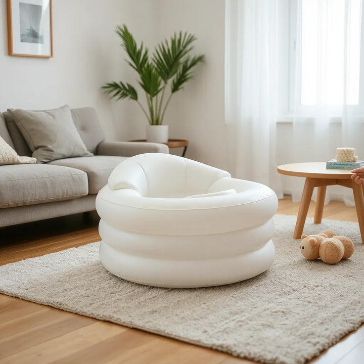 Uppblåsbar babystol i vardagsrumsmiljö med mjuk sits och förälders hand som justerar positionen